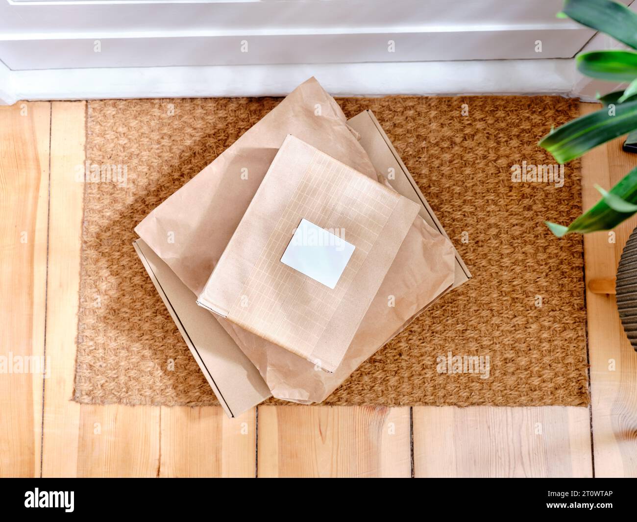 Stack of delivered cardboard parcels on a door mat next to apartment entrance Stock Photo