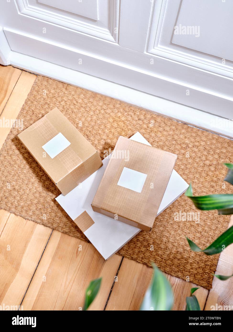 Stack of delivered cardboard parcels on a door mat next to apartment entrance Stock Photo