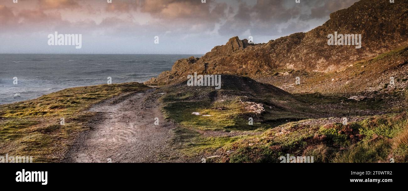 A panoramic image of evening light over a rough footpath on the rugged Pentire Point East on the coast of Newquay in Cornwall in England in the UK. Stock Photo