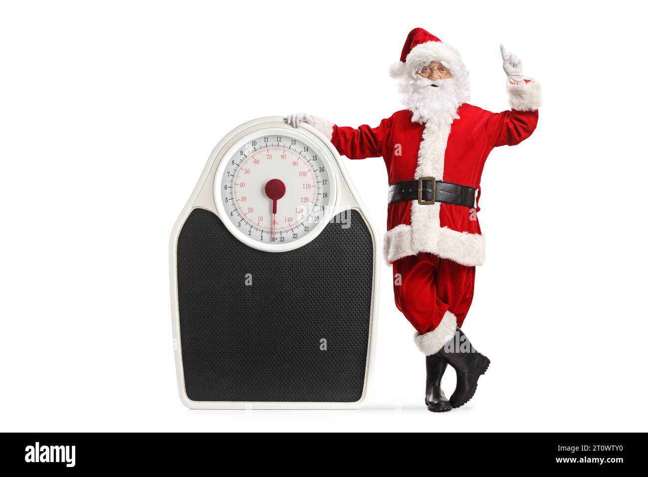 Santa Claus leaning on a big weight scale and pointing up isolated on white background Stock Photo