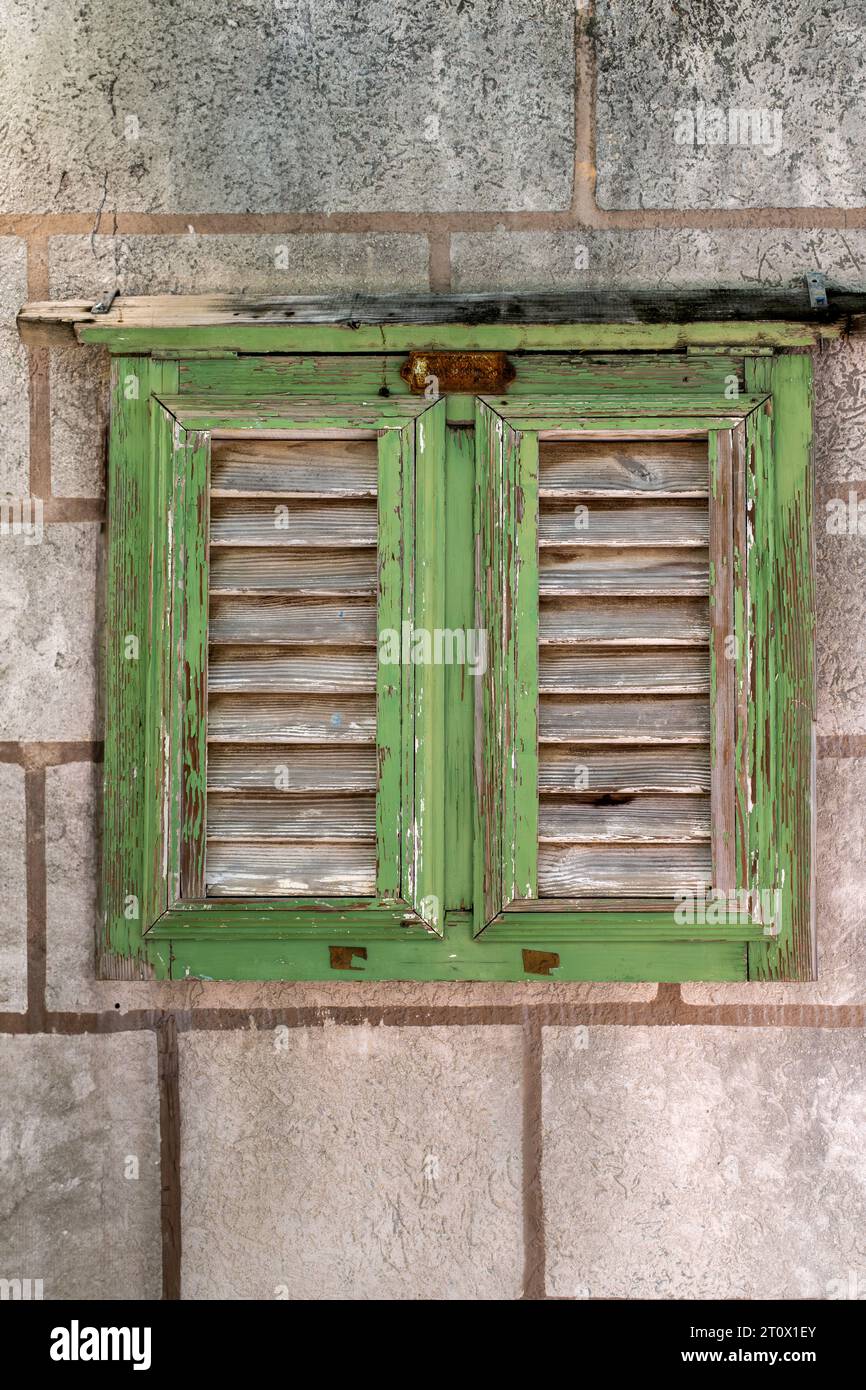 An old Window with a weathered green frame and shutters Stock Photo