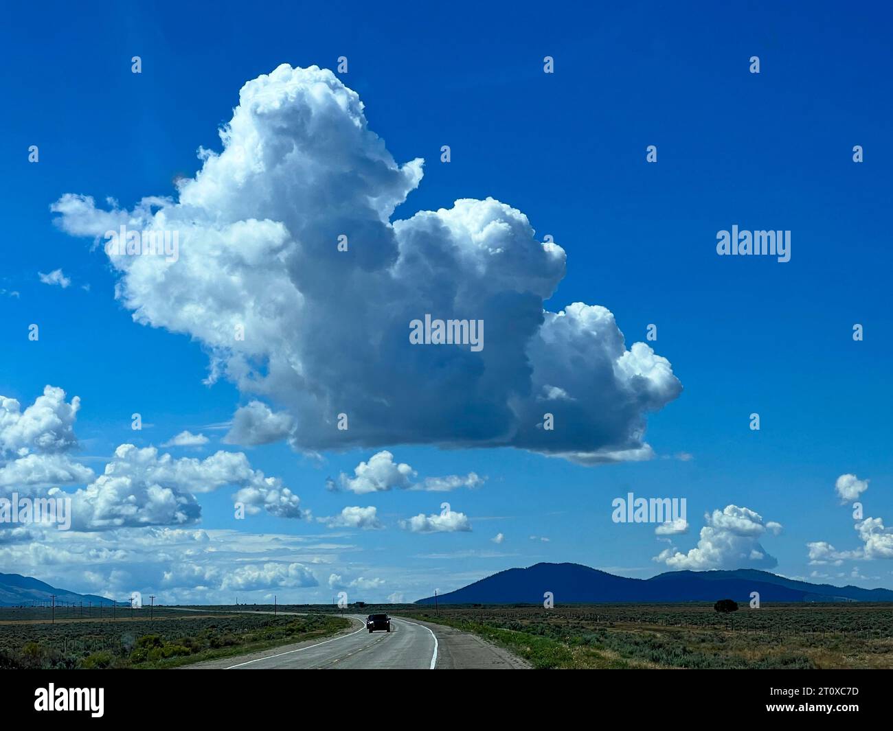 Cumulus clouds against a perfect blue sky over a Colorado byway Stock Photo
