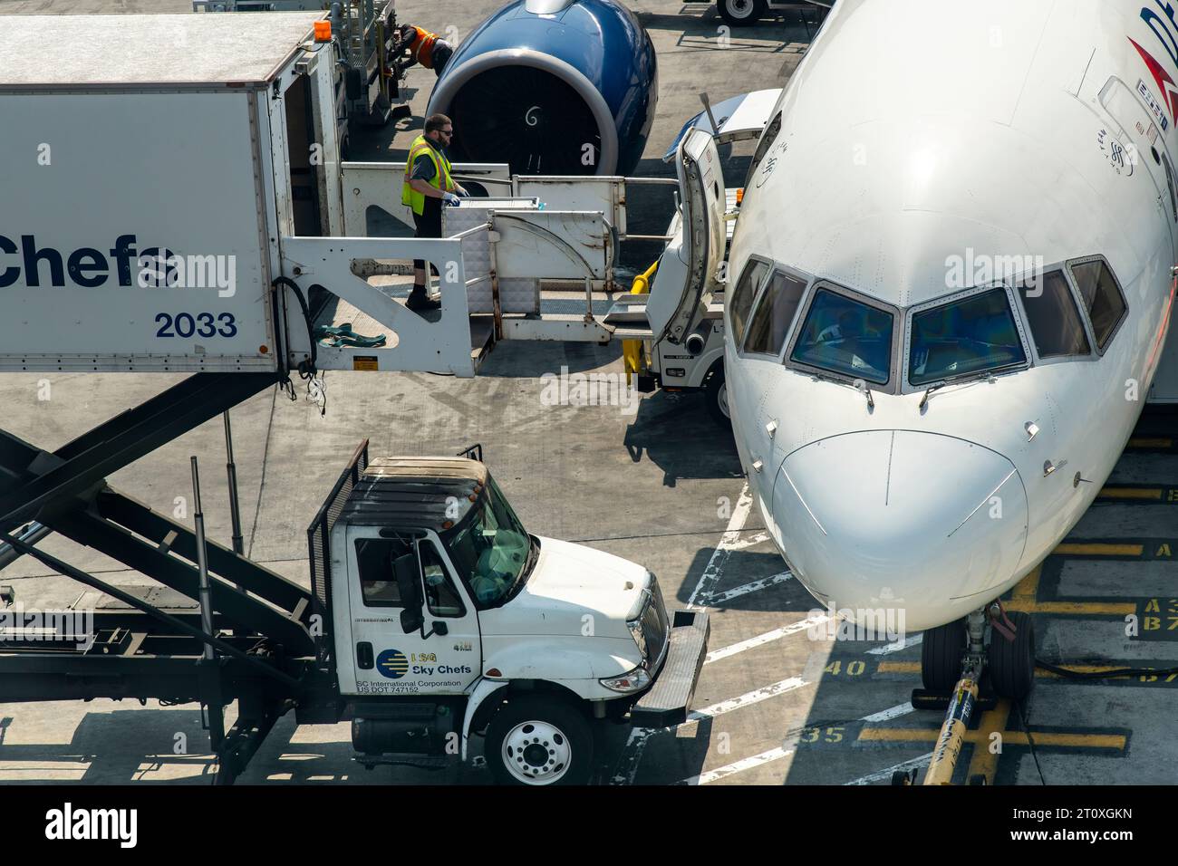 JFK Airport, NY, USA- July 11, 2023; Close up of one member of ground staff pushing catering cart into Delta aircraft from Airport catering truck Stock Photo