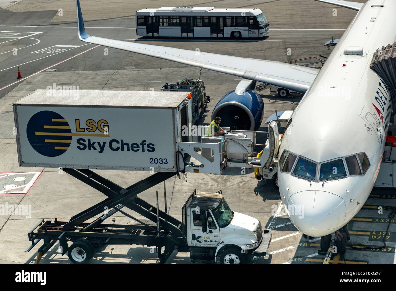 JFK Airport, NY, USA- July 11, 2023; Airport catering truck next to a Delta aircraft for food supply with one member of ground staff pushing catering Stock Photo