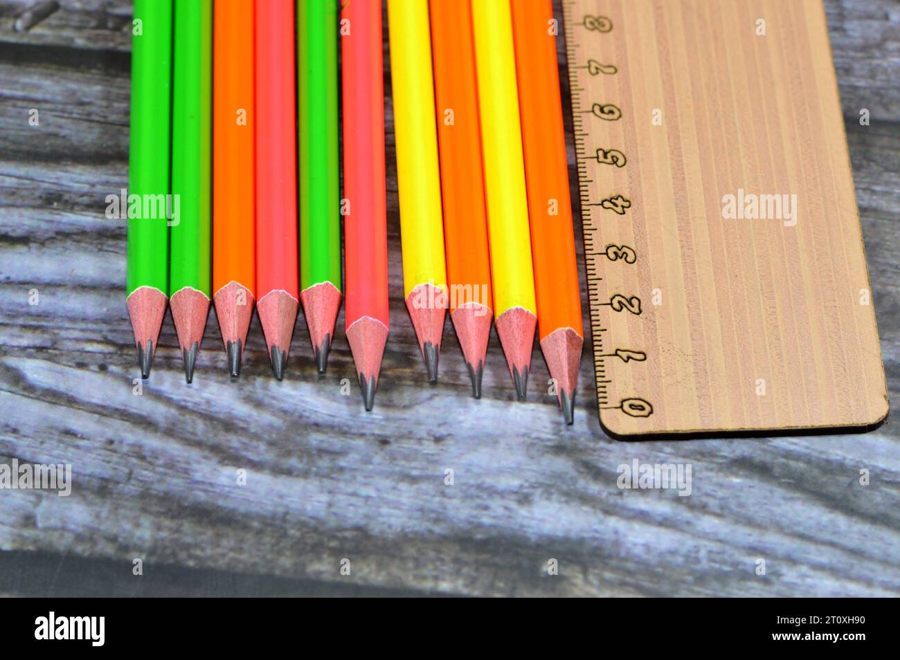 A ruler, rule, line gauge for length measurement and Row of pencils, a pencil is a writing or drawing implement with a solid pigment core in a protect Stock Photo