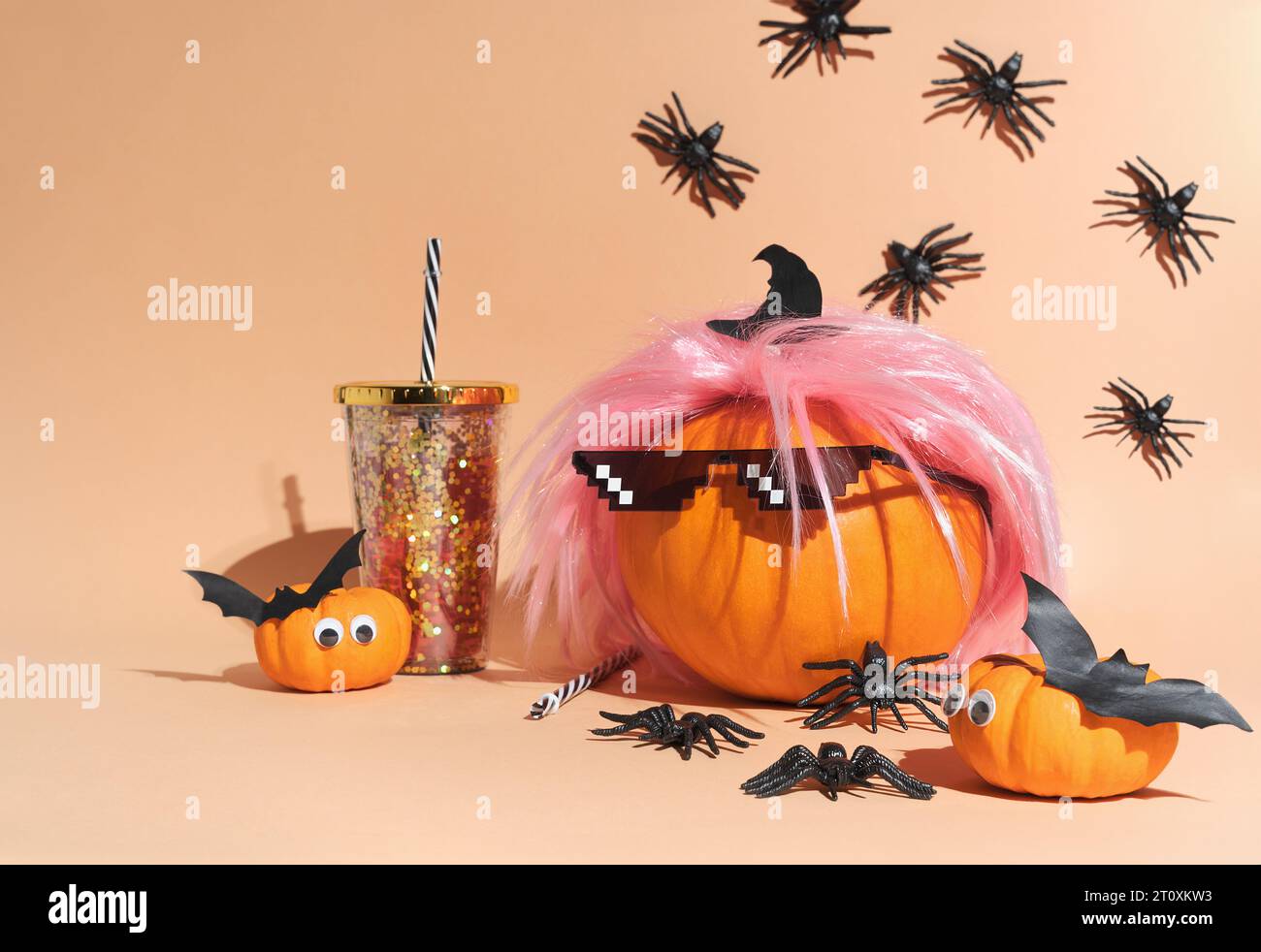 Creative pumpkin in pink wig and 8 bit sunglasses Deal with it. Retro style costume, 80s vibe style. Crawling spiders. Halloween party decoration. Cop Stock Photo