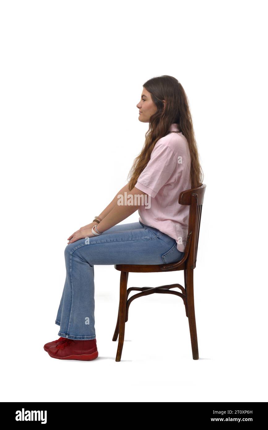 Side view of a young girl sitting on chair on white background Stock ...