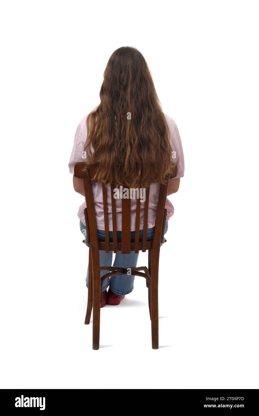 back view of a young girl sitting on chair on white background Stock