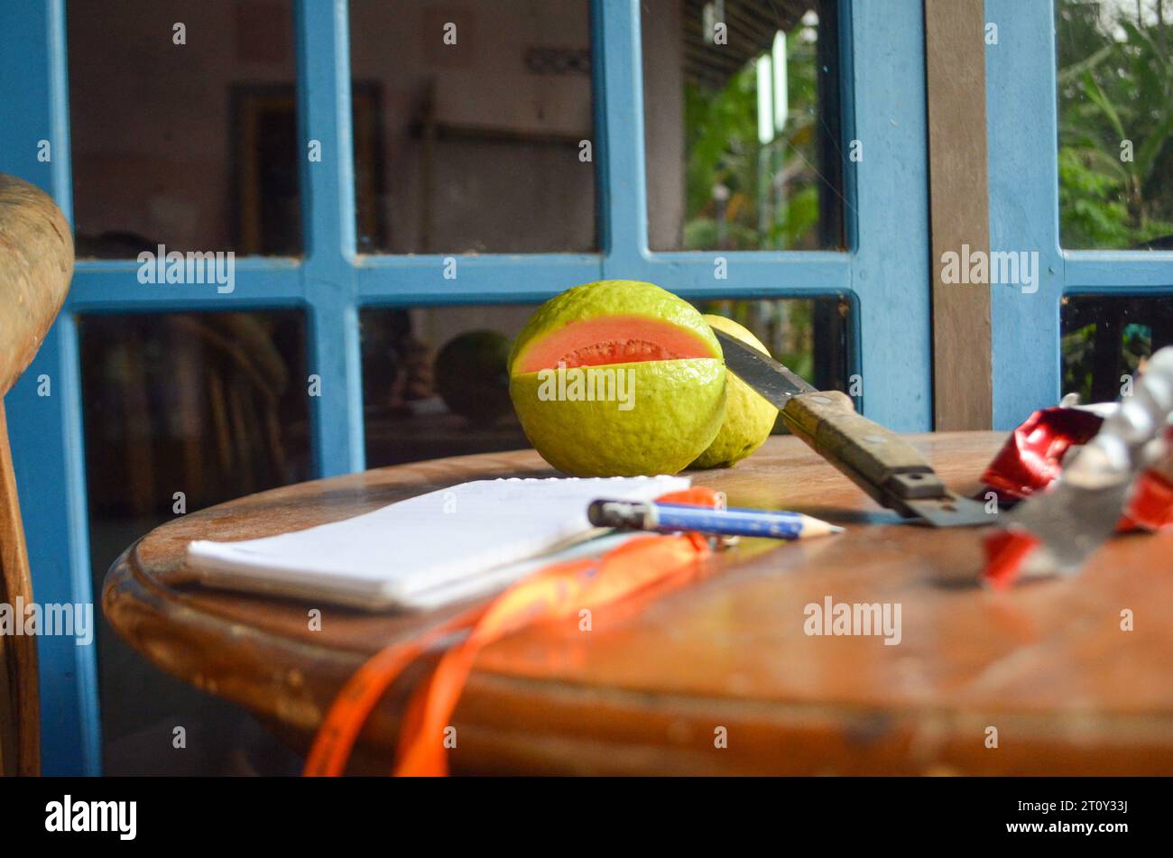 Photograph of several objects such as guava, pencil, knife, notebook on a wooden table,Indonesia Stock Photo