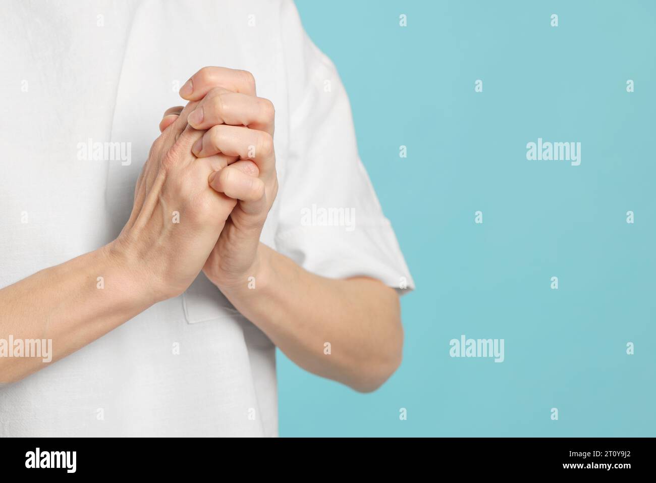 Woman cracking her knuckles on turquoise background, closeup and space