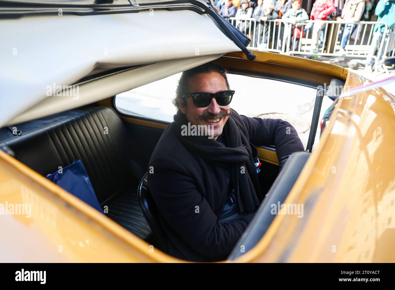 A man smiles while driving a 1970 Fiat up 5th Avenue in the Columbus