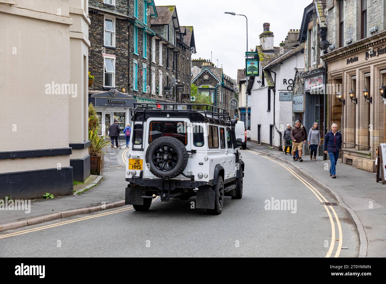 Land Rover Defender 100 white driving through Ambleside town centre,Lake District,Cumbria,England,UK Stock Photo