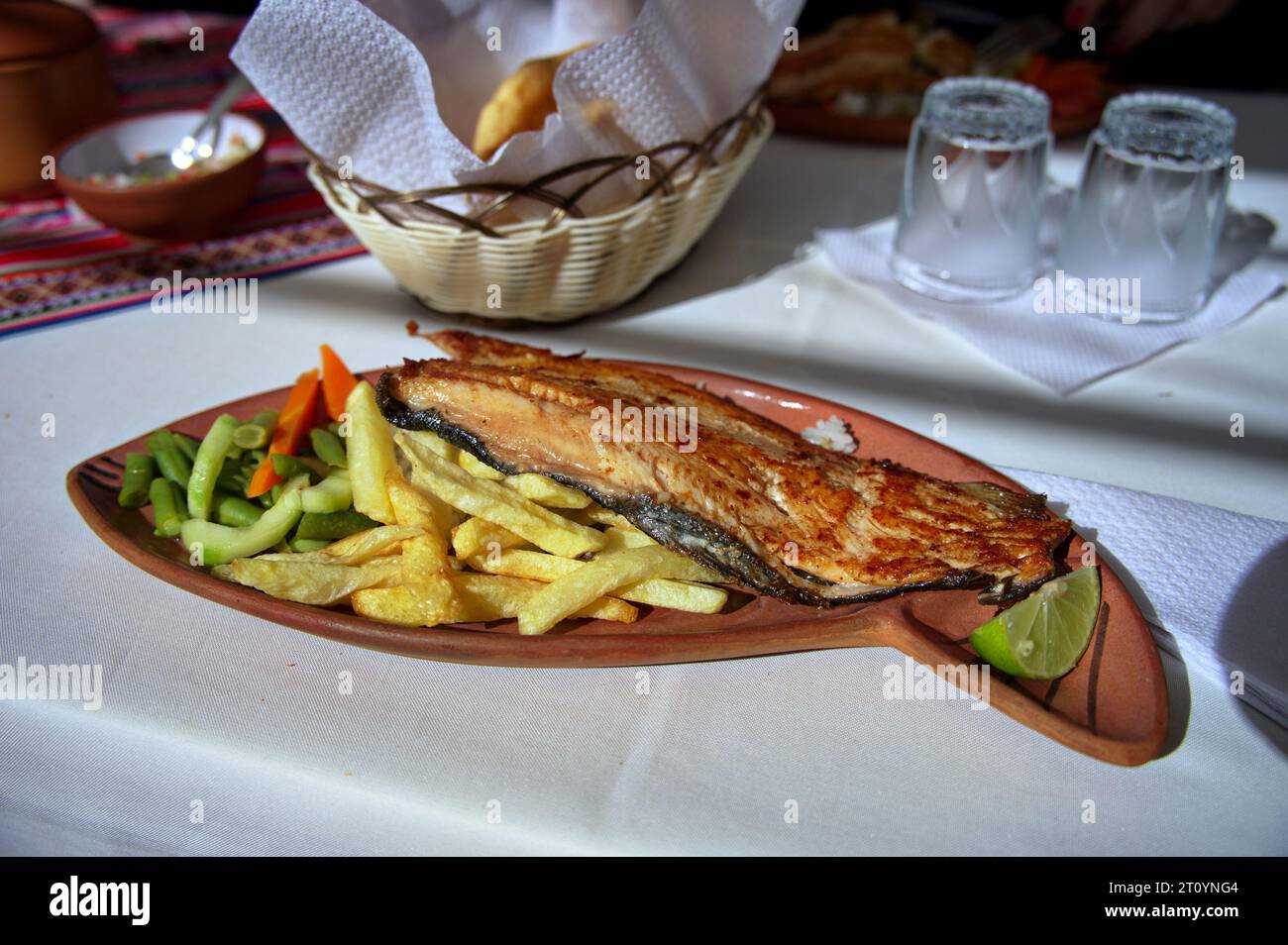 Fish, French fries and vegetables on the plate served in Peruvian village on lake Titicaca Stock Photo