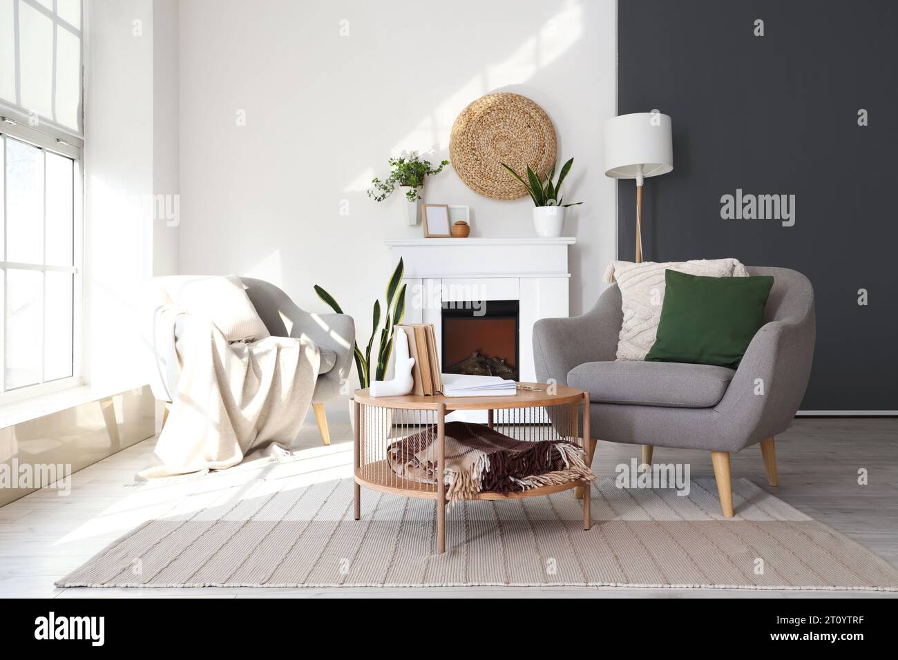 Interior of bright living room with armchairs, coffee table and fireplace Stock Photo