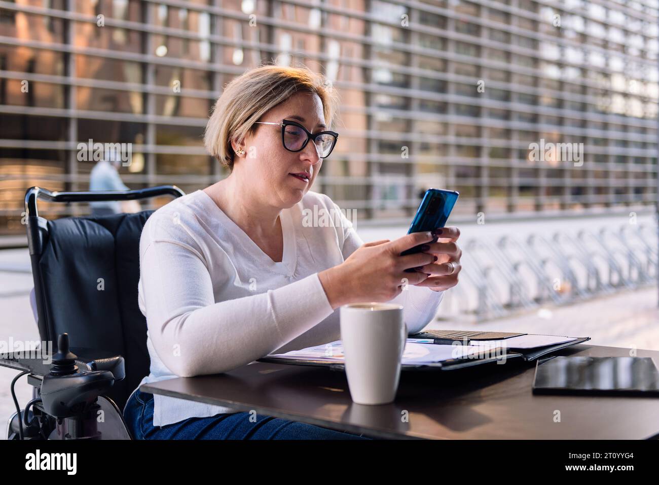 woman using wheelchair using mobile on a terrace Stock Photo