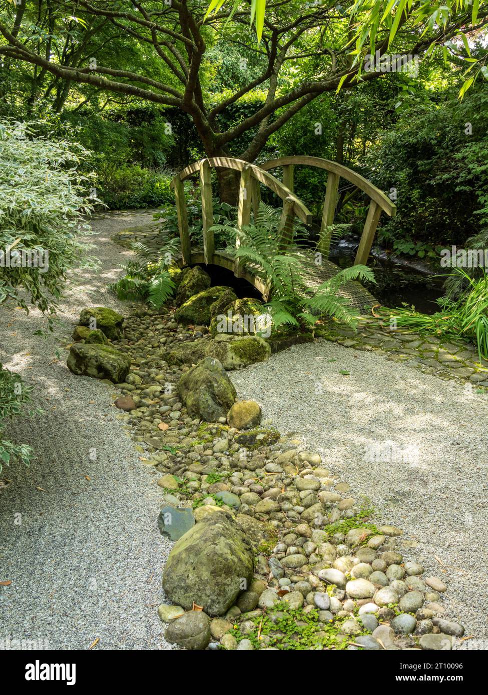 Japanese Zen styled garden with raked gravel, ornate wooden bridge and river of pebbles, Barnsdale Gardens, Rutland, England, UK. Stock Photo