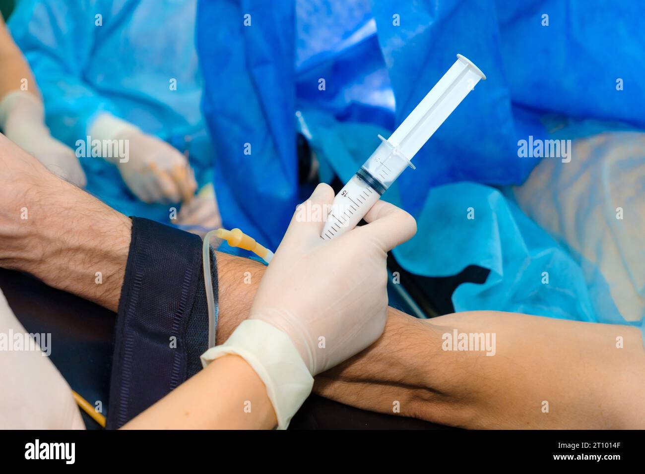 The hands of an anesthesiologist in sterile gloves inject intravenous