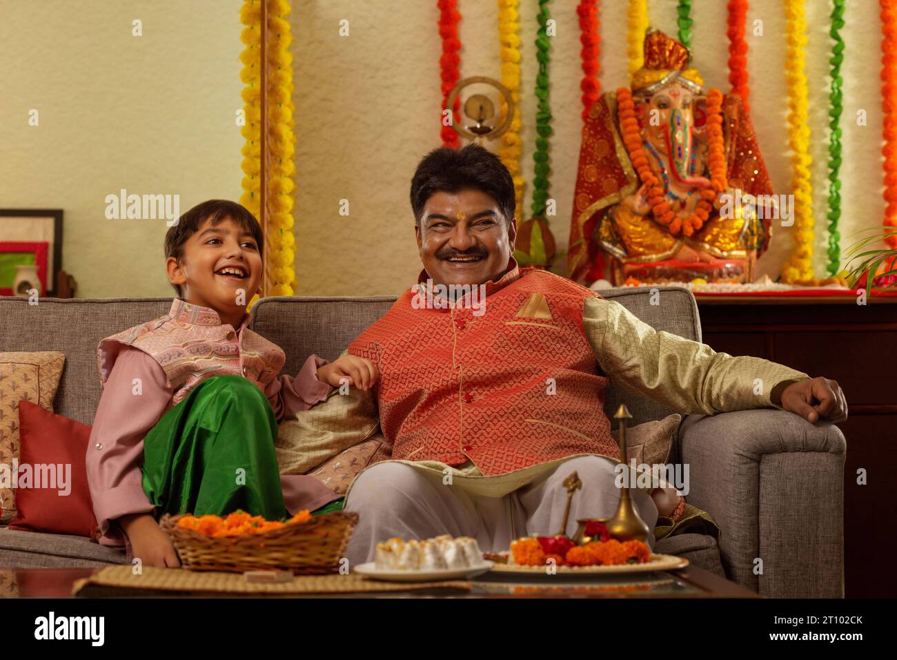 Portrait of grandfather with his grandson sitting together in living room on the occasion of Ganesh Chaturthi Stock Photo