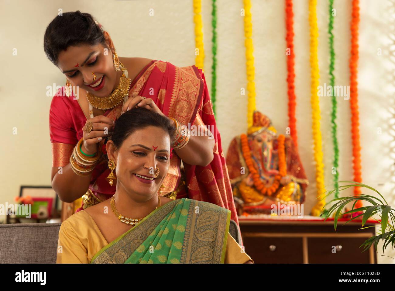 Daughter-in-law helping her mother-in-law while getting ready on the occasion of Ganesh Chaturthi Stock Photo