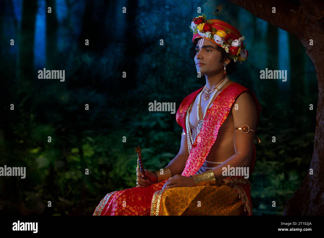 Young man dressed up as Lord Krishna on the occasion of Janmashtami Stock Photo