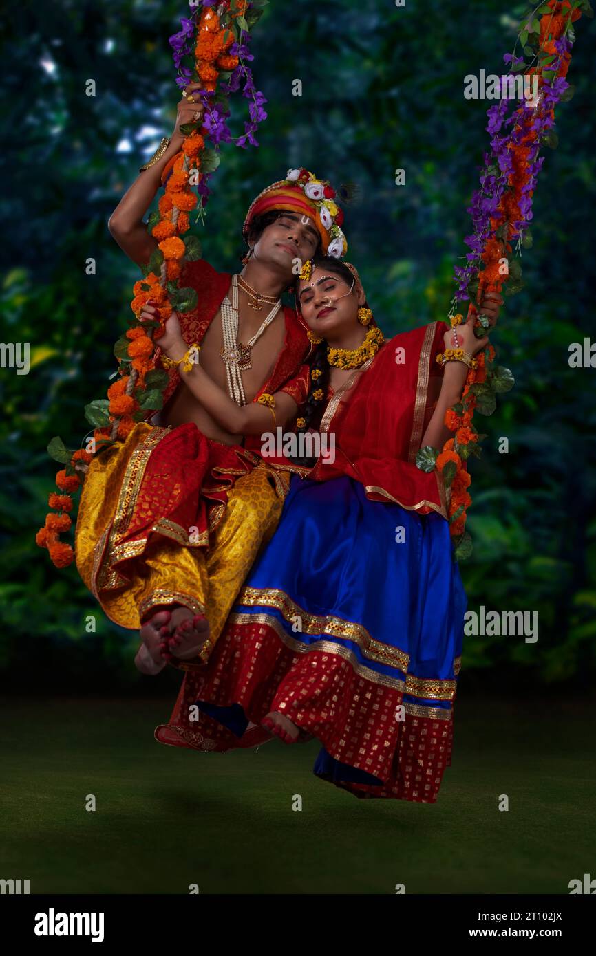 Young man and woman dressed up as Radha and Krishna and swinging