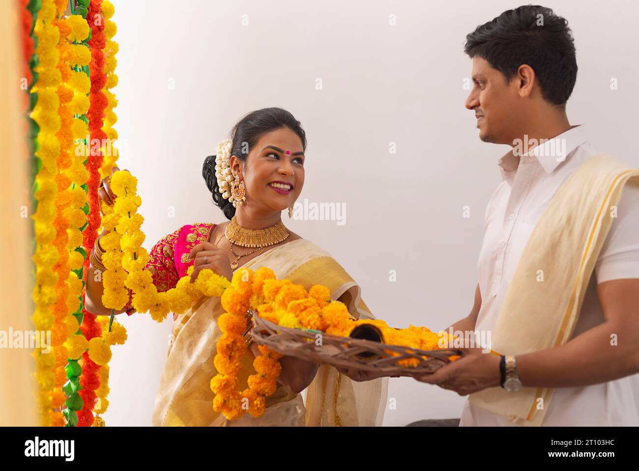 South Indian couple decorating house with flower garland to celebrate