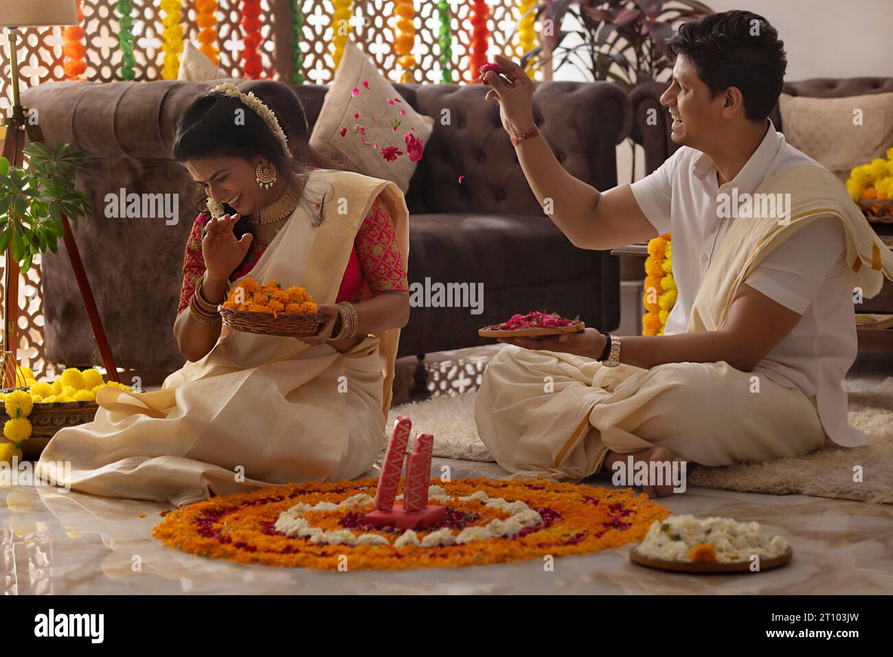 Loving husband throwing rose petals on his wife while decorating house on Onam Stock Photo
