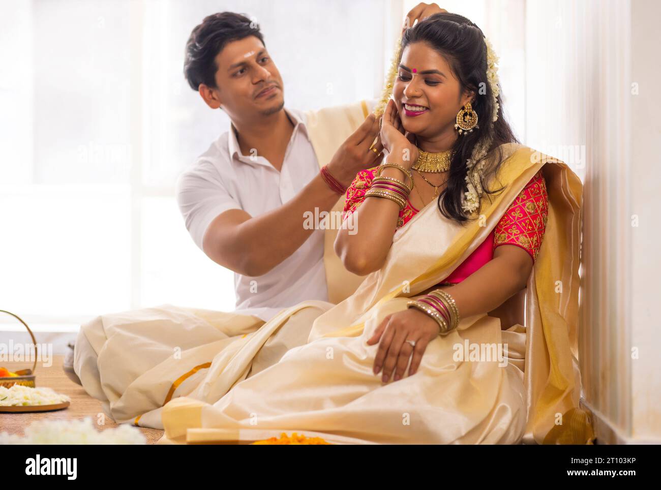 Husband helping his wife to get ready on Onam Stock Photo
