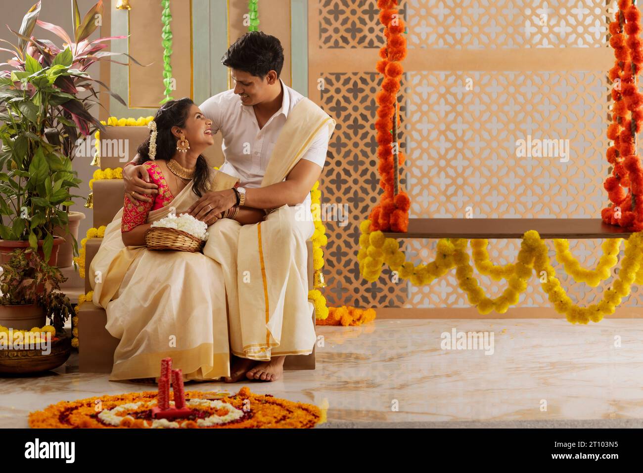 South Indian couple decorating house with flower garland to celebrate