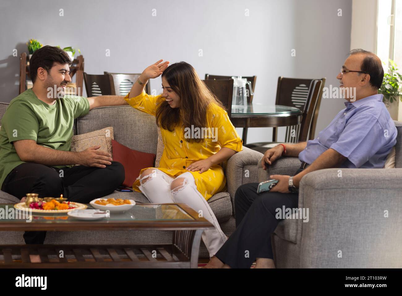 Happy Indian family sitting together at home and talking to each other on Raksha Bandhan Stock Photo