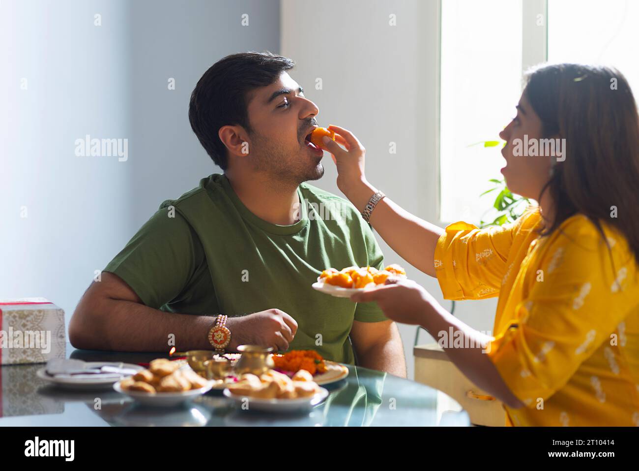 Sister feeding laddoo to her brother on Raksha Bandhan Stock Photo