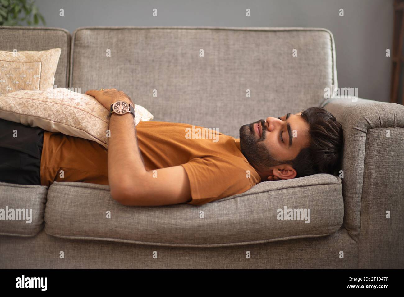Portrait of young man sleeping on sofa in living room Stock Photo