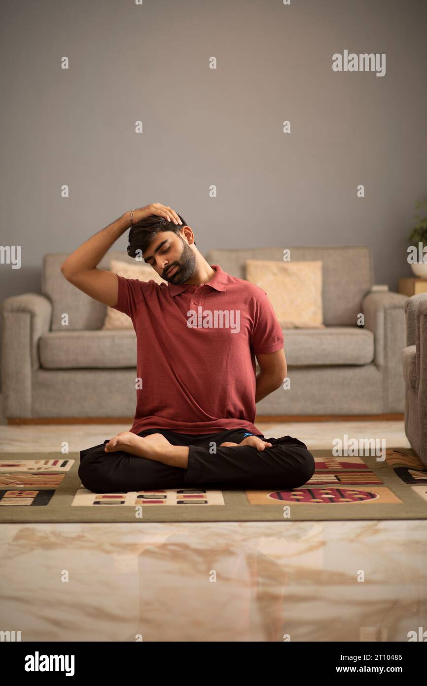 Young man meditating in living room Stock Photo