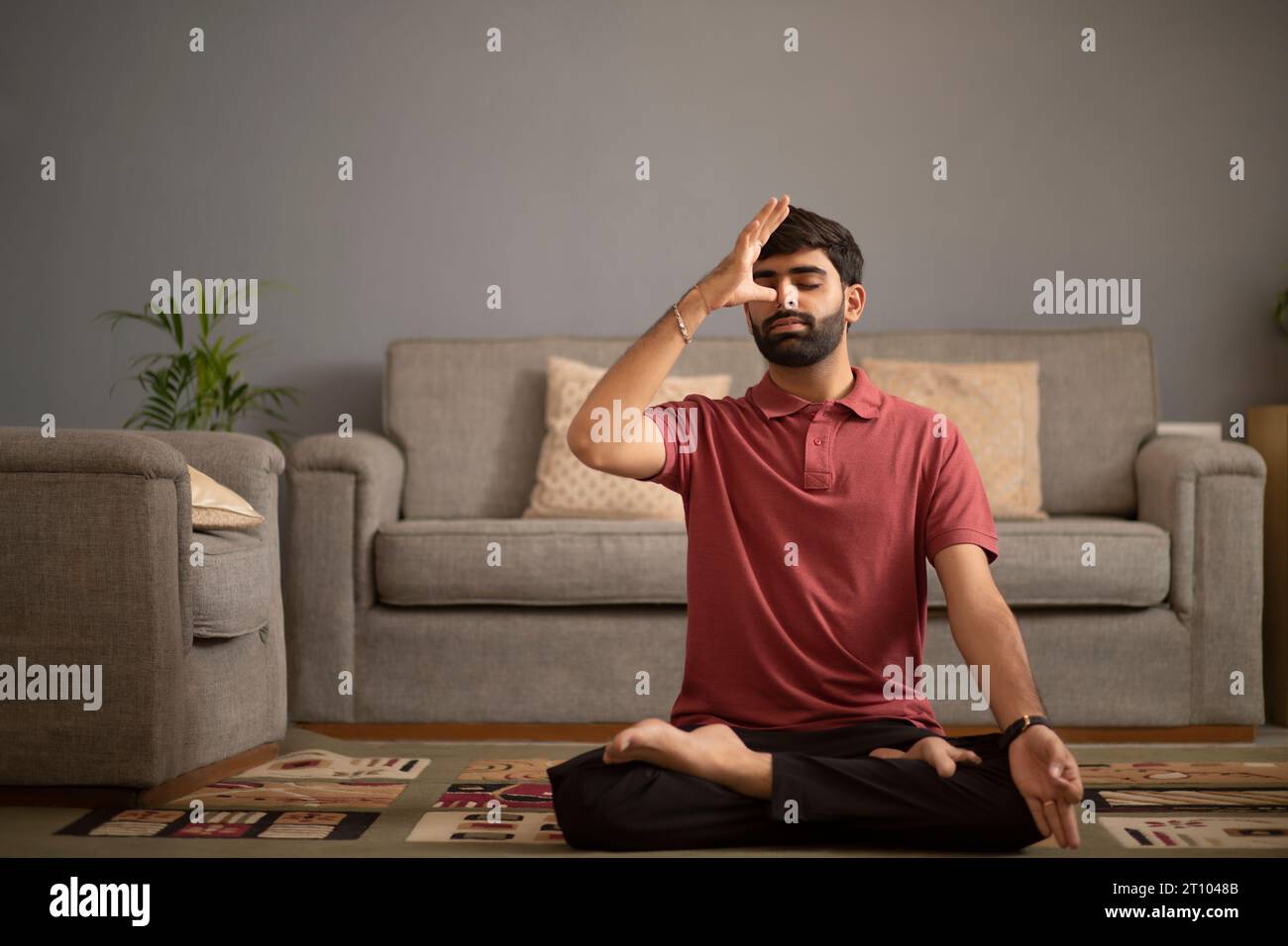 Young man meditating in living room Stock Photo