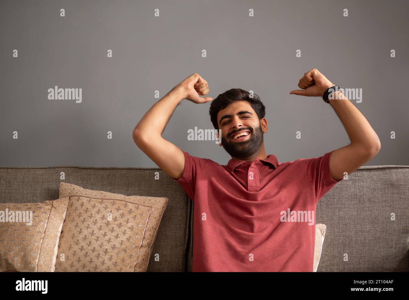 Young man cheering while sitting on sofa in living room Stock Photo