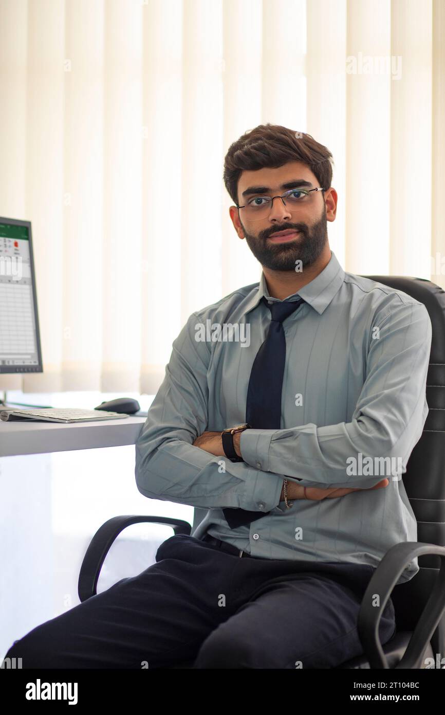 Portrait of confident young man sitting at desk in the office Stock Photo