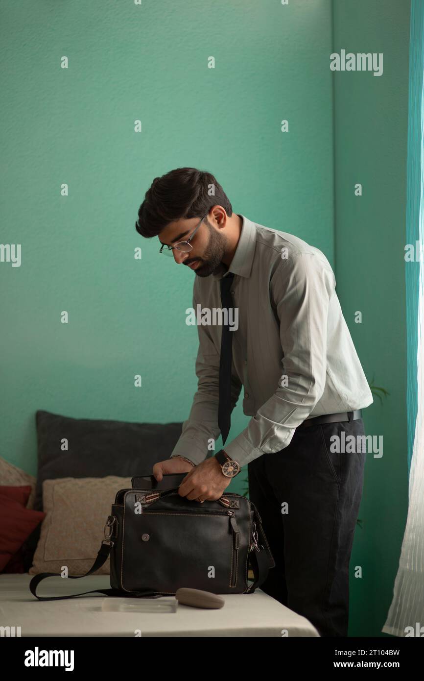 Young man packing his bag while getting ready for office Stock Photo