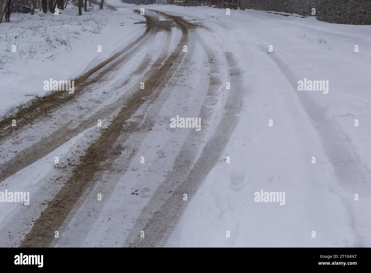 Car tracks on a snowy road. Slippery road, danger, risk of skidding. Traces of winter tire treads. Stock Photo