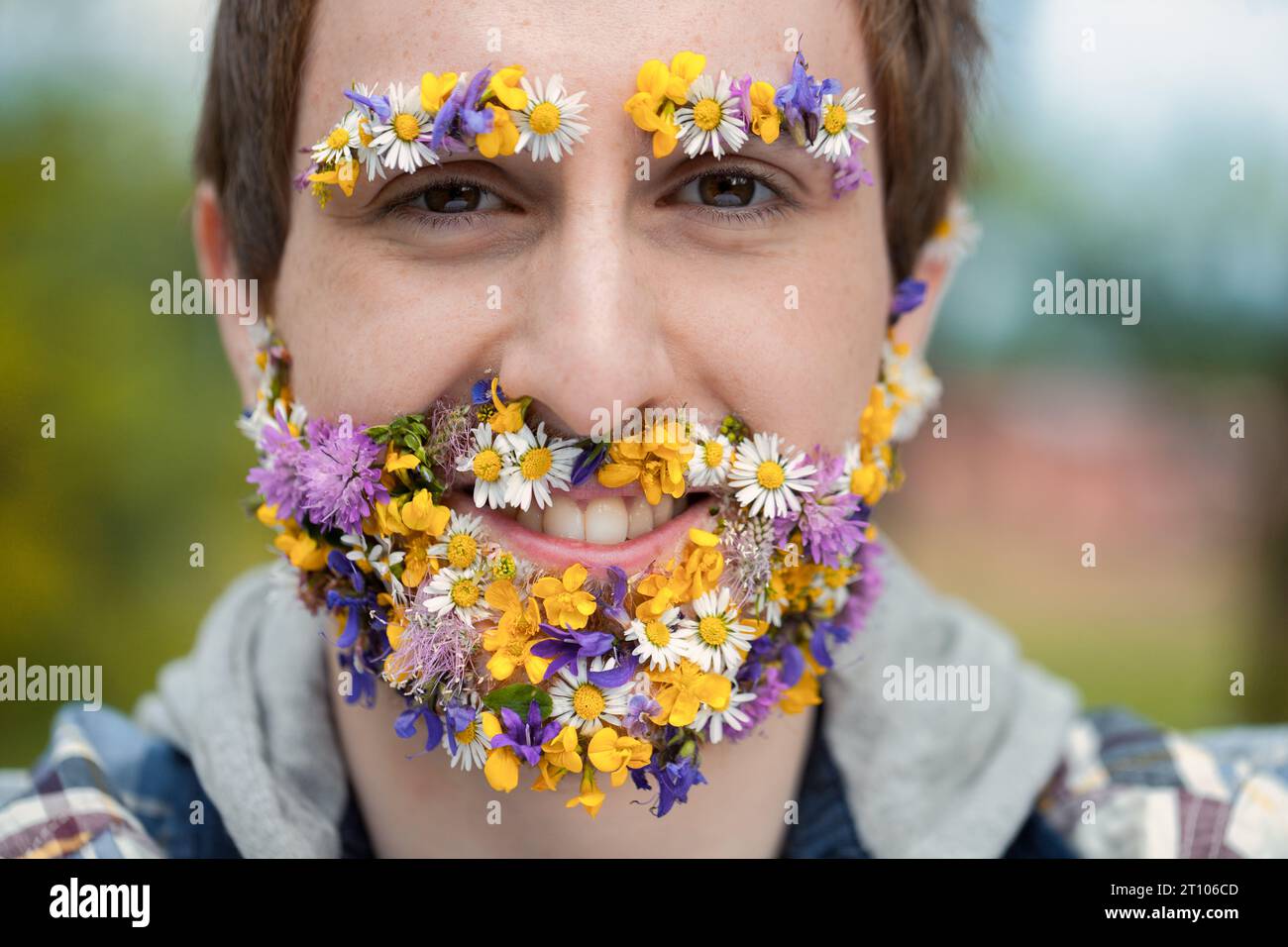 man's face is a floral canvas in the forest. This, either a vivid imagination or reality, stresses his bond with the environment. Cherishing peace, he Stock Photo