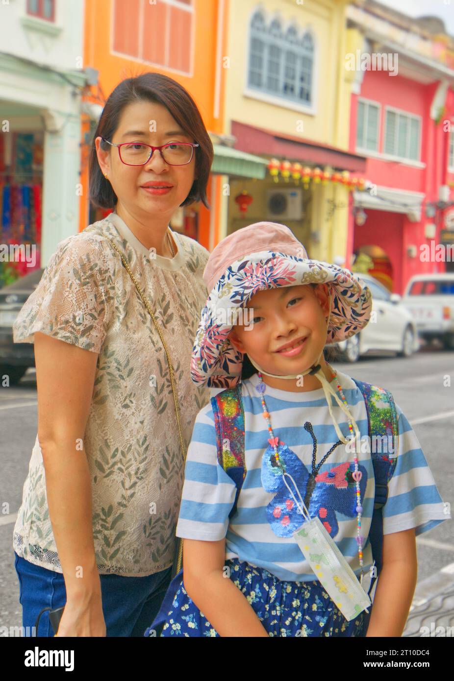 Portrait of Asian mother and little daughter traveling in the old town of Phuket, middle-aged single mother and 8-9-year-old child girl, vertical imag Stock Photo