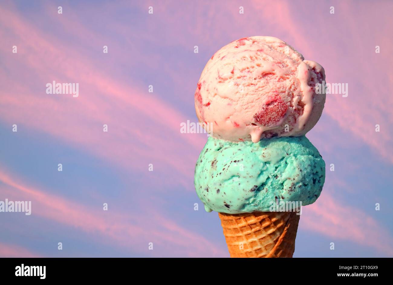 Two scoops of melting ice cream cone on pink evening sky background Stock Photo