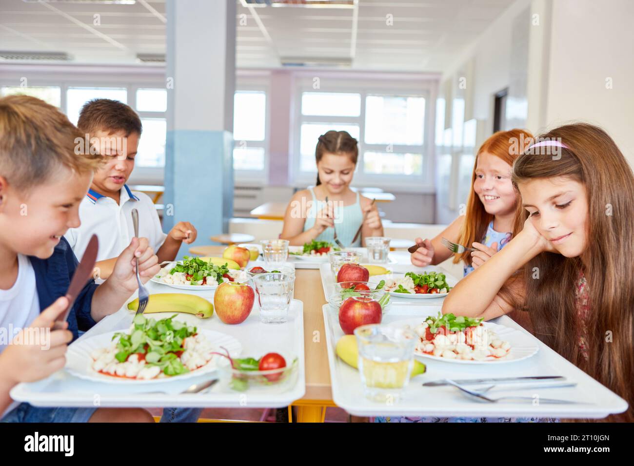 Happy male and female students eating food while sitting together in