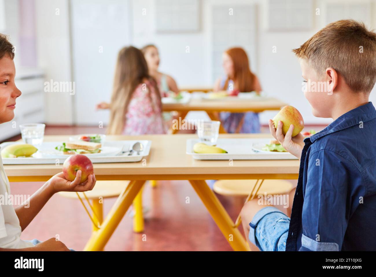 https://c8.alamy.com/comp/2T10JXG/male-friends-eating-apples-while-sitting-together-at-table-in-school-during-lunch-time-2T10JXG.jpg