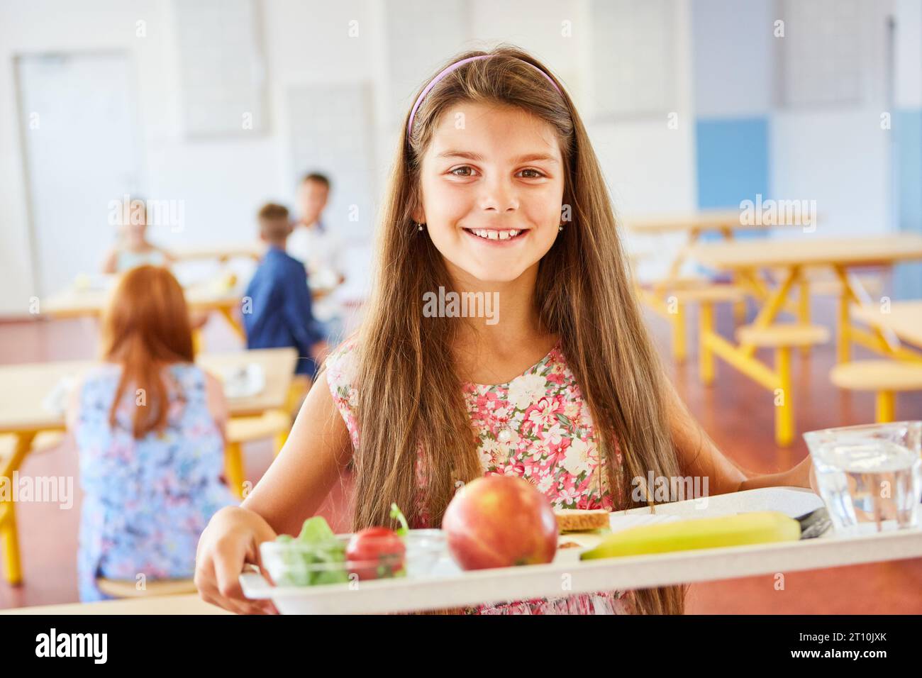 Portrait of happy schoolgirl with food tray standing in school cafeteria Stock Photo