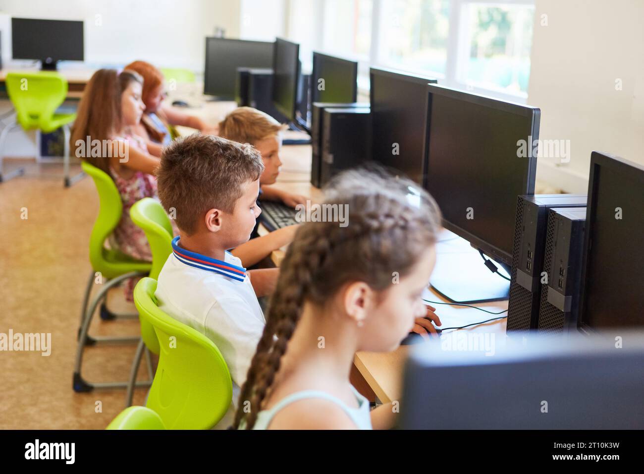 Male and female students using computers while sitting at desk in classroom Stock Photo