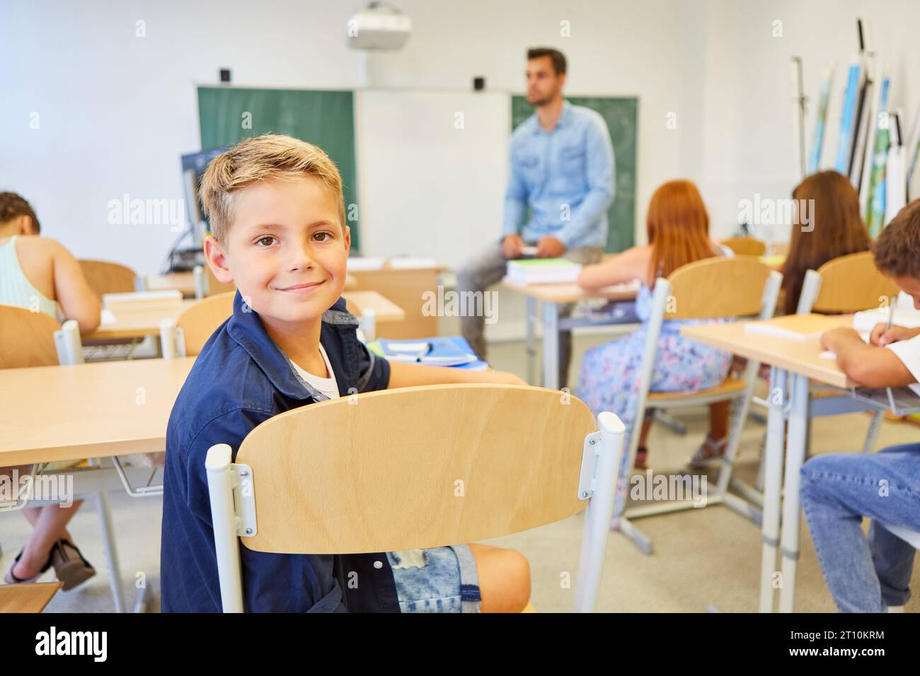 Portrait of smiling male elementary student sitting on chair in ...