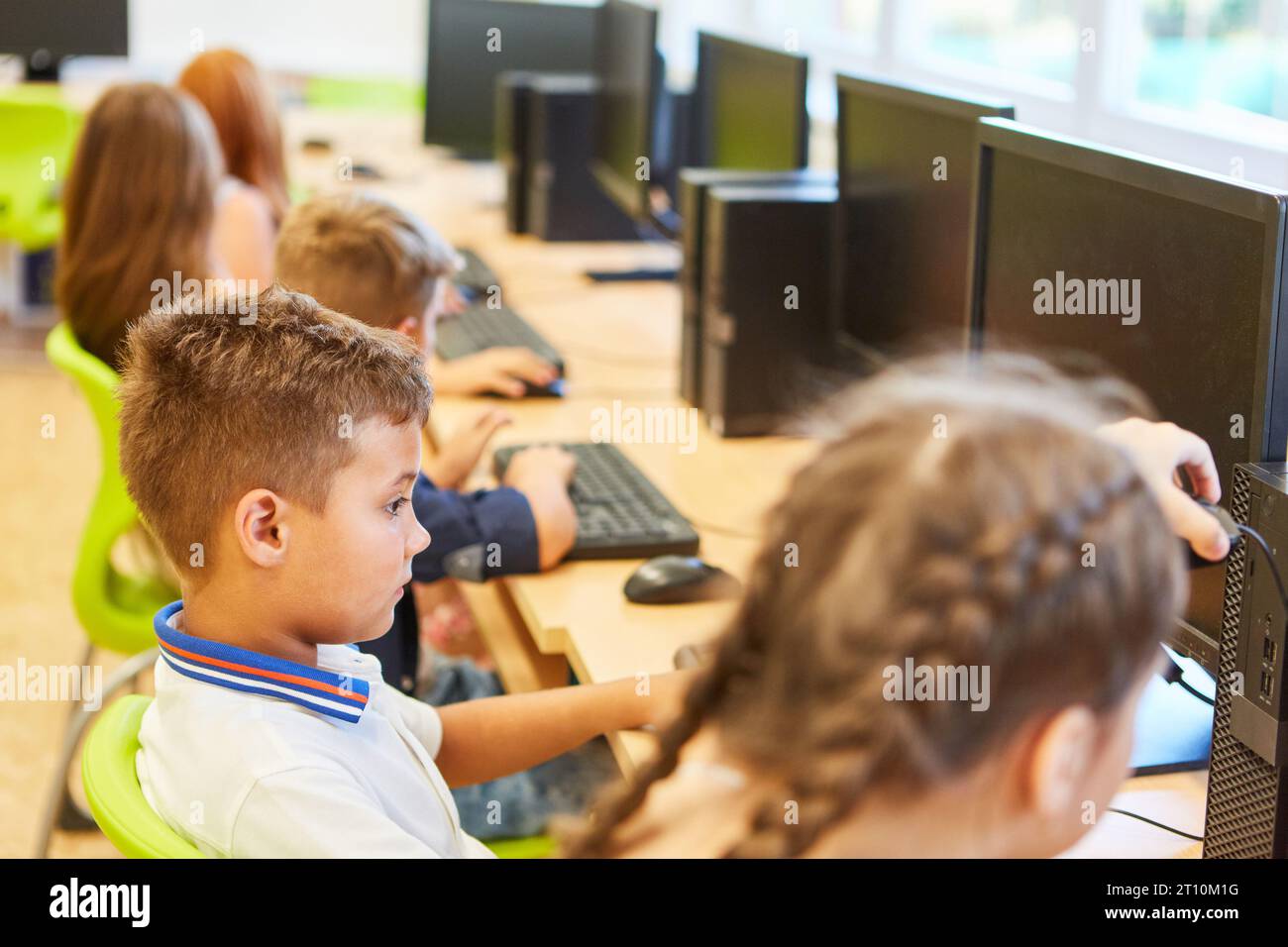 Schoolkid sitting with friends in computer class at school Stock Photo