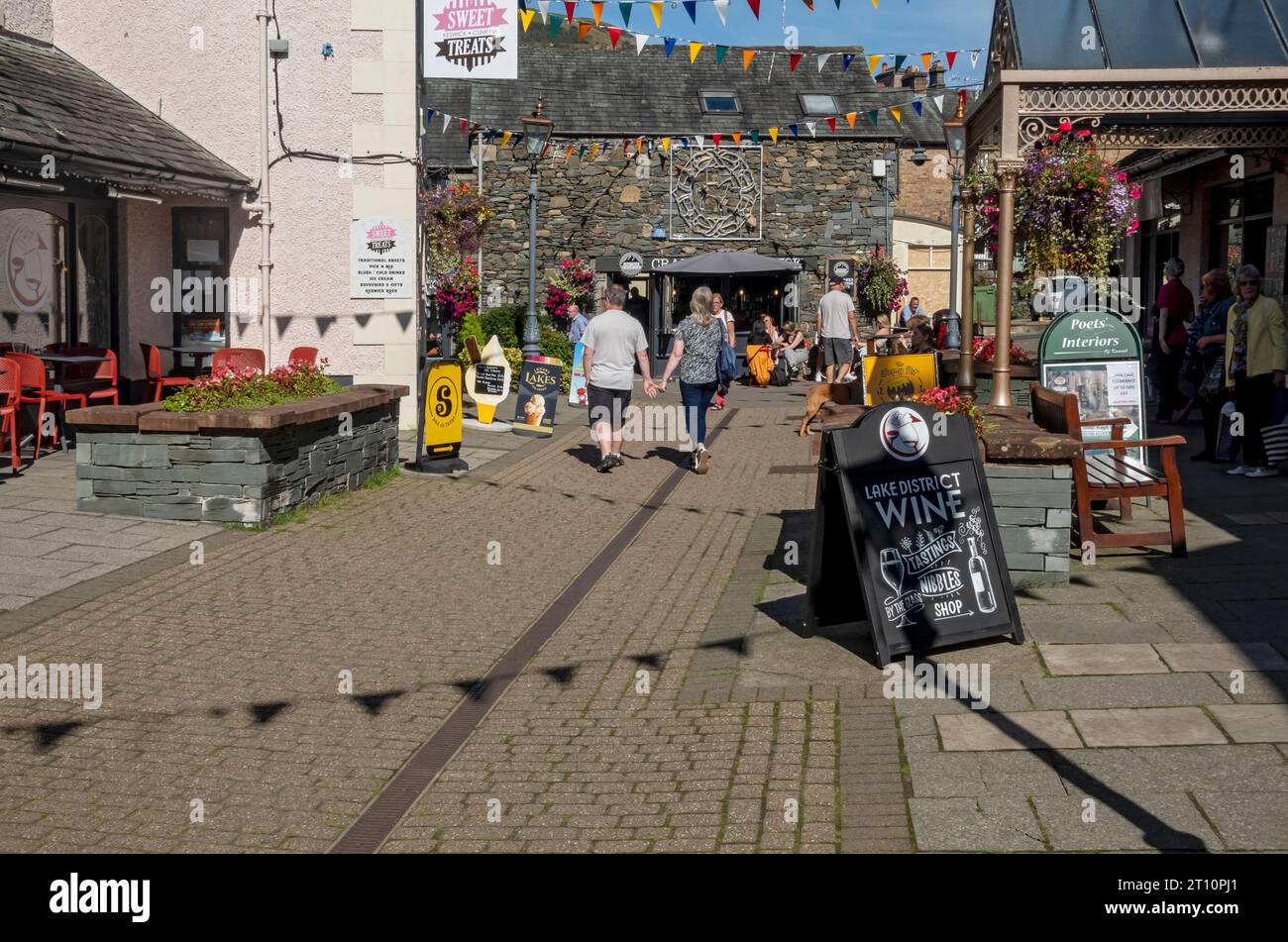 People tourists visitors walking around Packhorse Court shop shops shopping centre street in summer Keswick Cumbria Lake District England UK Britain Stock Photo