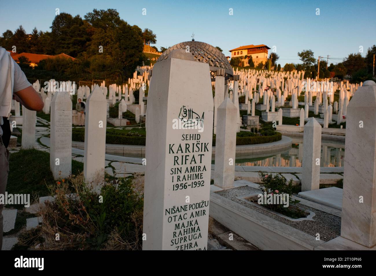 A single soldier's tombstone stands resolute in the soft glow of sunset, a poignant tribute to bravery and sacrifice in Sarajevo's hallowed grounds. Stock Photo