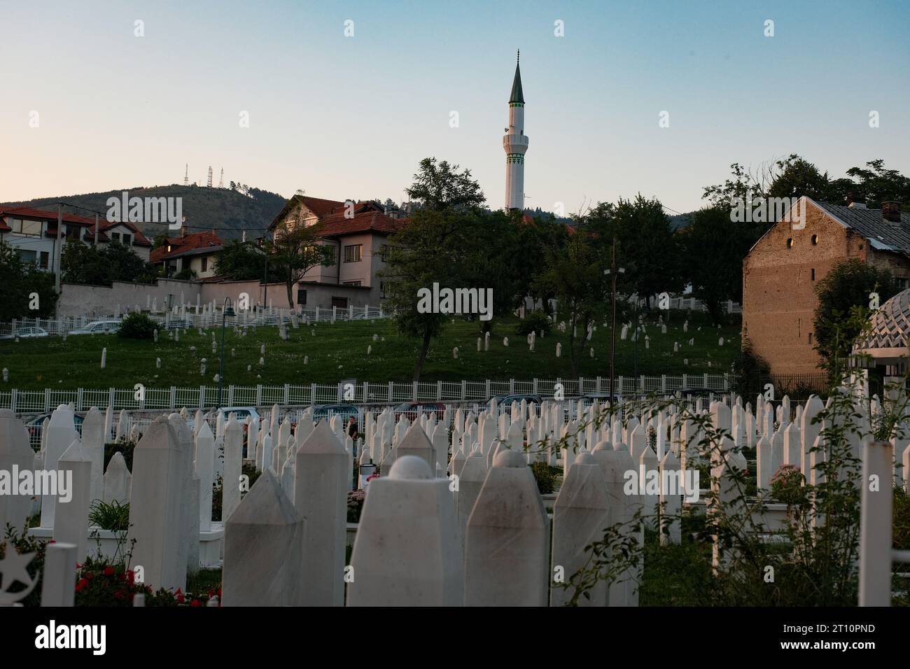 Sarajevo's soldier cemetery at sunset, where a lone soldier's grave, framed by a distant mosque, reflects the harmonious coexistence of history and fa Stock Photo